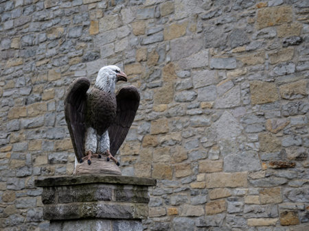 Old carved stone eagle sculpture on pillar by wall. With copyspace.