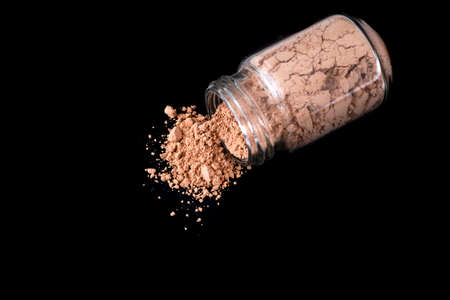 Red clay powder in small glass bottle, on black. Beauty cosmetic.の写真素材
