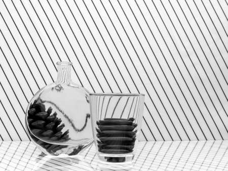 Black and white monochrome water distortion, reflection, refraction through glass and bottle. With pine cones.の写真素材