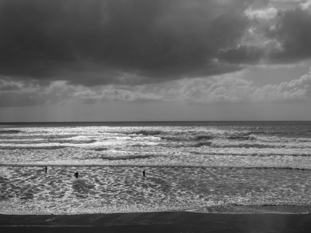 Bad weather seascape off north Devon coast with unidentifiable surfers and swimmer.