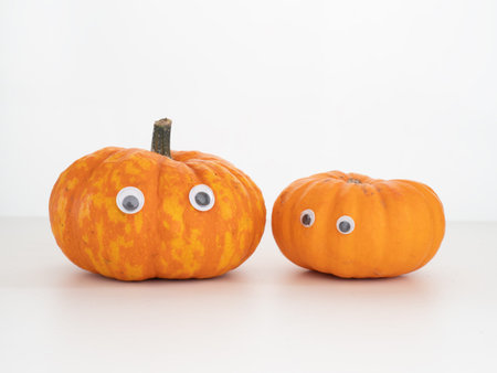 Two small pumpkins, squashes with stuck on eyes. Halloween maybe.