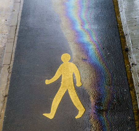 Pedestrian pavement sign with oil and water rainbow effect on asphalt. Eco oil concept.の写真素材