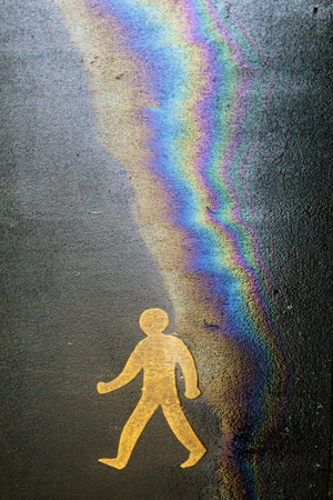 Pedestrian pavement sign with oil and water rainbow effect on asphalt. Eco oil concept.の写真素材