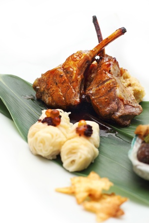 Lamb rack with eel mashed potato served on banana leaf placed on white background の写真素材