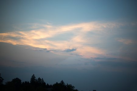 Evening sky with clouds and green treesの写真素材