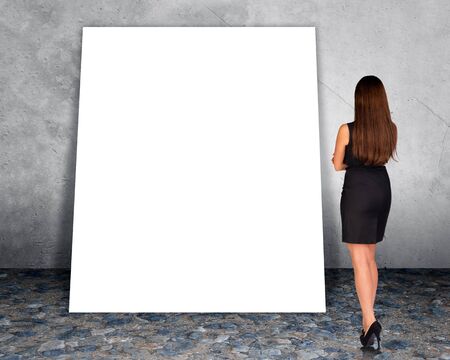 Big blank banner with businesswoman on grey wall background, rear viewの写真素材