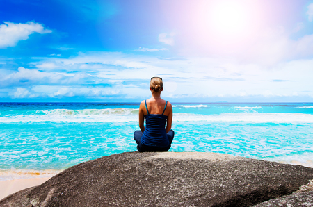 Young woman meditates on the beachの写真素材