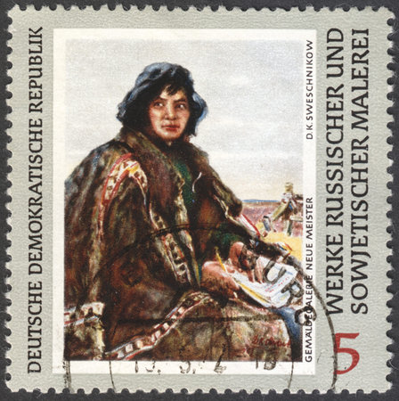 MOSCOW, RUSSIA - CIRCA FEBRUARY, 2016: a stamp printed in DDR shows a painting "Siberian Teacher" by Svechnikov, the series "Russian Paintings" circa 1969のeditorial素材