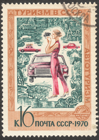MOSCOW, RUSSIA - CIRCA APRIL, 2016: a post stamp printed in the USSR shows a woman and a car, the series "Tourism in the USSR", circa 1970のeditorial素材