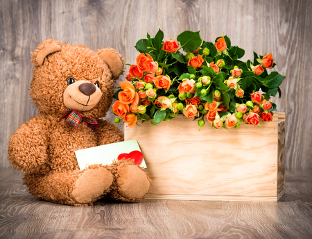 Flowers and a teddy bear on wooden backgroundの写真素材