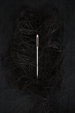 Needle and black thread on black background