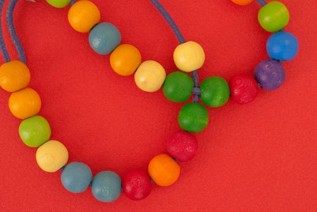 Red background with colored wooden pearlsの写真素材