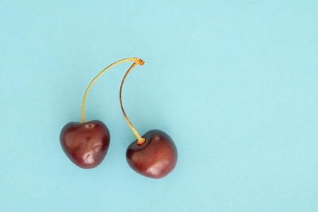 Two cherries on blue paper backgroundの写真素材