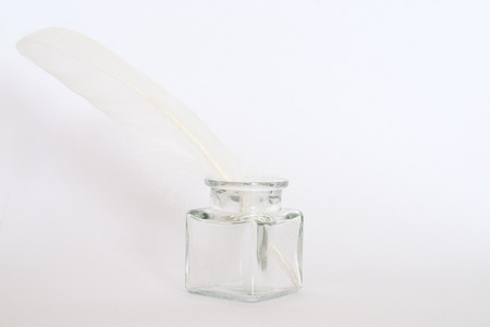 white feather and ink pot on white paperの写真素材