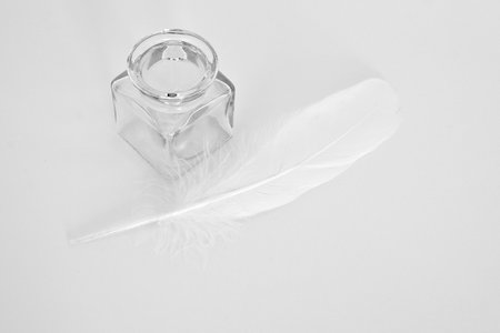 white feather and ink pot on white paperの写真素材
