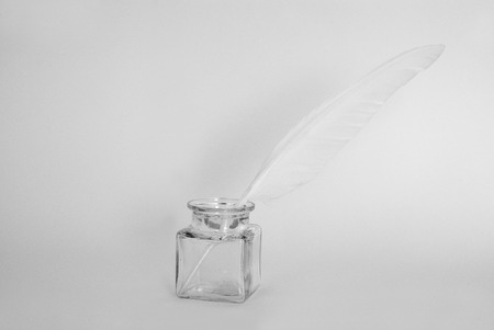 white feather and ink pot on white paperの写真素材