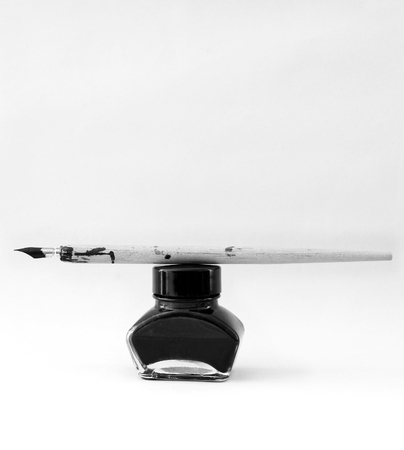 ancient pen and black ink pot on white paperの写真素材