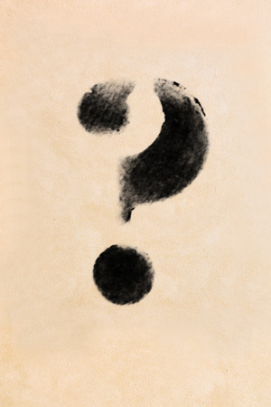 Old black, frayed grunge question mark on brown paperの写真素材