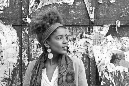 head shot of young afro american woman in front of old damaged wall background- black and white...
