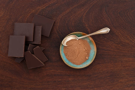 close up of  a silver spoon, chocolate and cacao powder on wooden background - studio shot  from...