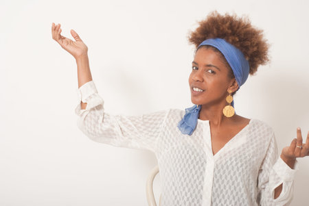 Head shot of young afro american curly woman profile in front of white wall backgroundの写真素材