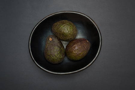 Avocado - tropical fruit in a bowl - studio shot on black background from above natural greenery, trend color, color of the year 2017の写真素材
