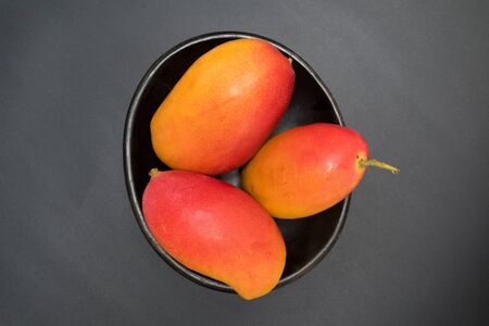 mangoes - tropical fruits in a bowl - studio shot on black background from aboveの写真素材
