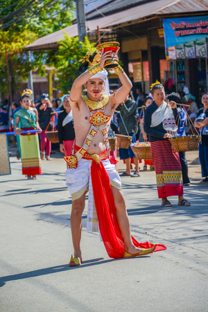 CHIANGMAI, THAILAND - JANUARY 25, 2015: Indigenous Dancer man with traditional costume holding tray with pedestal of flower dancing in parade of 22nd Traditional Skirt Fabric and The Indigenous Product and Culture Festival in Mae Chaem, Chiangmai, Thailanのeditorial素材