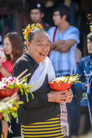 CHIANGMAI, THAILAND - JANUARY 25, 2015: Smiling indigenous senior woman with tray with pedestal of flowers  in parade of 22nd Traditional Skirt Fabric and The Indigenous Product and Culture Festival in Mae Chaem, Chiangmai, Thailandのeditorial素材
