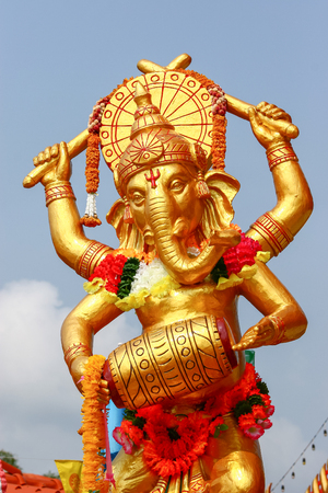 Golden Ganesha, lord of success, statue decorated with flowers.の写真素材