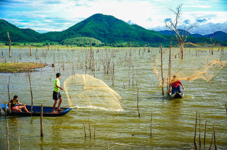 Kanchanaburi, Thailand - July 14, 2012: Fishermen on boat casting fishing net to catch fish in swamp in rural of Thailandのeditorial素材