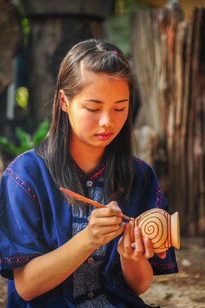 Udonthani, Thailand - December 10, 2012: Beautiful artist woman painting on earthenware which is rural small enterprise in Udonthani, Thailandのeditorial素材