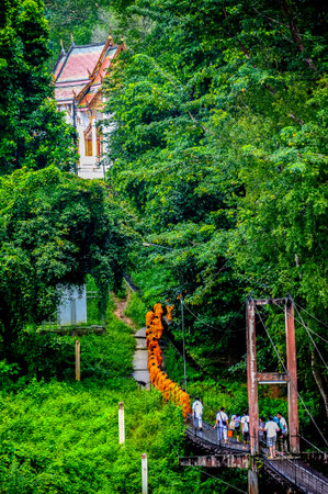 Kanchanaburi, Thailand - September 15, 2012: Buddhist monks marching on wooden bridge to get back to...