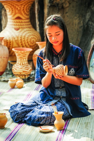 Udonthani, Thailand - December 10, 2012: Beautiful artist woman painting on earthenware which is rural small enterprise in Udonthani, Thailandのeditorial素材