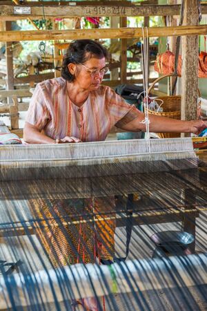 Chiangrai, Thailand - February, 24, 2013: Woman in rural weaving cotton in her own house, this is the second occupation in addition to agriculture in Chiangrai, Thailandのeditorial素材