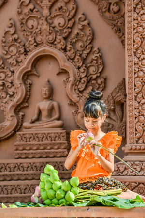 Kanchanaburi, Thailand - December 14, 2014: Girl with traditional dresses folding lotus petal for being used to worship Buddha image in Buddhist church in Kanchanaburi, Thailandのeditorial素材