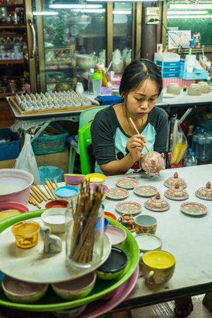 Samut Sakhon, Thailand - January 21, 2018: Woman artist painting ceramic pottery in factory house where is small medium enterprise in Samut Sakhon, Thailandのeditorial素材