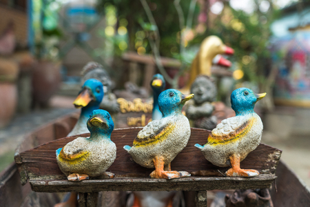 Sculpture of ceramic duck on wooden bench to decorate garden area around houseの写真素材