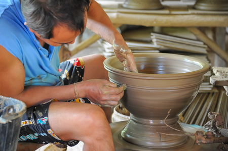 Sukhothai, Thailand - July 10, 2011: Senior craftsman making ceramic pottery from clay by using electrical motor rotation machine to form the figure of pottery in the workshop in Sukhothai, Thailandのeditorial素材
