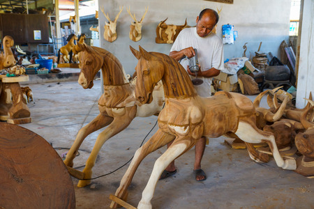 Lampang, Thailand - November 3, 2012: Craftsman polishing wooden horse sculpture with polishing machine for furniture in the workshop in Lampang, Thailandのeditorial素材