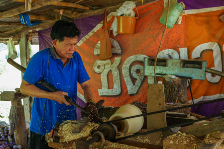 Lampang, Thailand - November 3, 2012: Carpenter lathing a piece of wood by using lathe machine to make furniture from wood in the workshop in Lampang, Thailandのeditorial素材