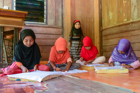 Krabi, Thailand - May 2, 2015: Cute Muslim girls drawing pattern on Batik fabric for painting in their home in Krabi, Thailandのeditorial素材