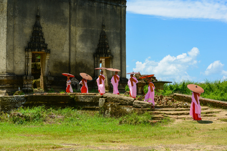 Kanchanaburi, Thailand - July 24, 2016: Group of Mon nuns in pink robes holding umbrella walking toward to ruined Buddhist church in Kanchanaburi, Thailandのeditorial素材