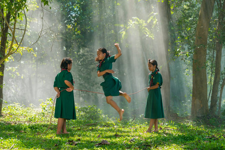Sakonnakhon, Thailand - July 31, 2016: Three girls in school uniform playing jumping game together on field in rural of Sakonnakhon, Thailandのeditorial素材
