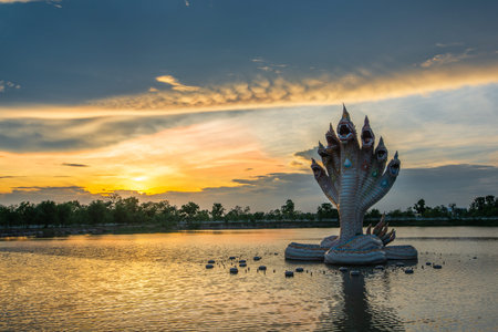 Beautiful Naga statue during sunset in Wat Ban Rai Buddhist temple in swamp, the tourists...