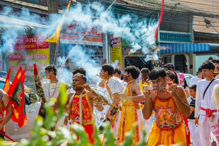 Phang Nga, Thailand - October 15, 2018: Group of men demonstrating sharp steel run through the mouth while firecracker being fired in vegetarian festival parade in Phang Nga, Thailandのeditorial素材