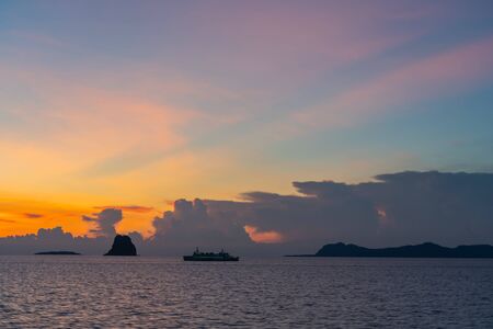 Silhouette unidentified ferry ship running sea during beautiful sunsetの写真素材