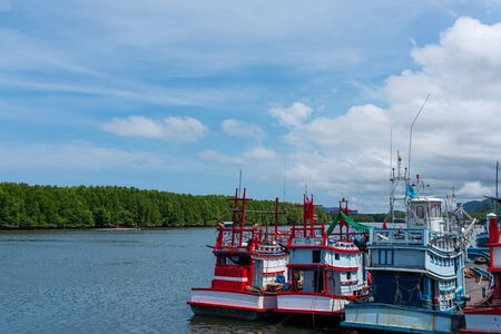 Fishing ships parking at estuary in fisherman village in sunny blue sky dayの写真素材