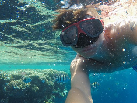 A man with an underwater mask swims near the corals in the Red Sea, engaged in divingの写真素材