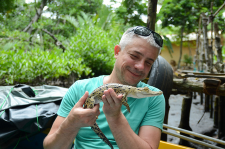 A man holds in hands a small crocodile. Jungle of Sri Lankaの写真素材